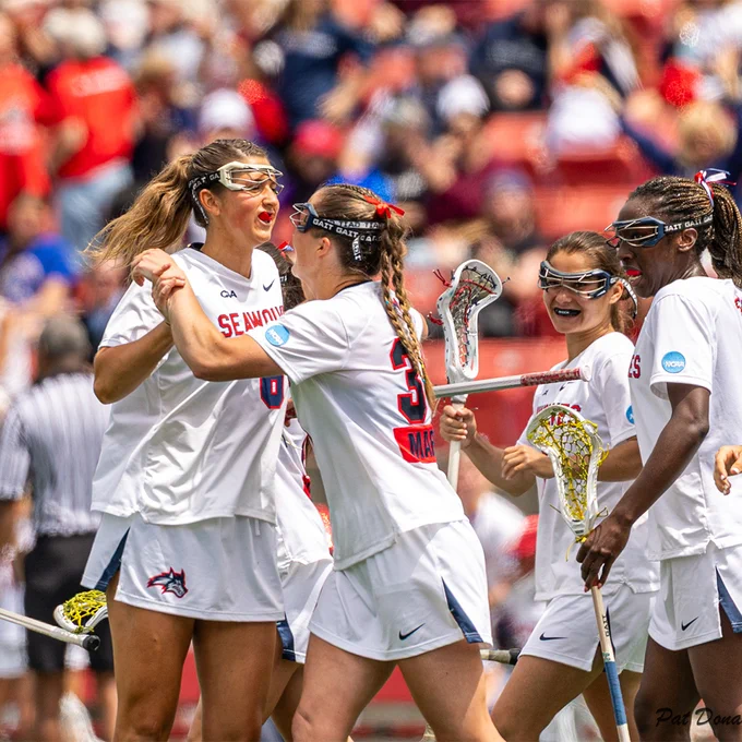 Stony Brook women’s lacrosse players celebrate together during a game.