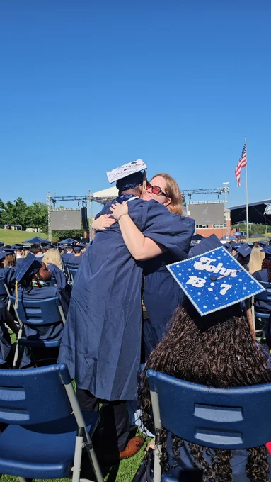 A graduate hugging a volunteer at commencement.