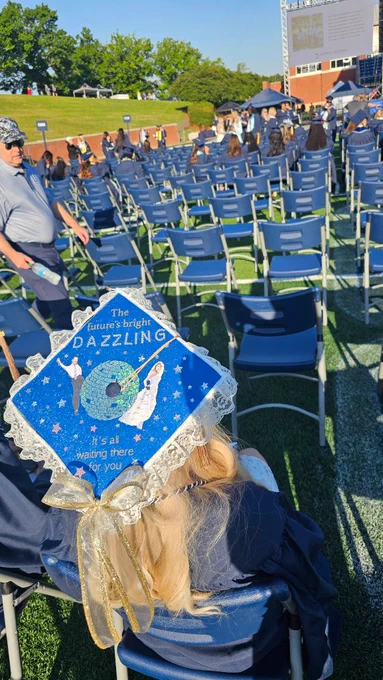 A graduate cap decorated with lace, stars, and sparkles. There is a disco ball and images of Harry Styles and Taylor Swift. There is text that says, "The future's bright. Dazzling. It's all waiting there for you."