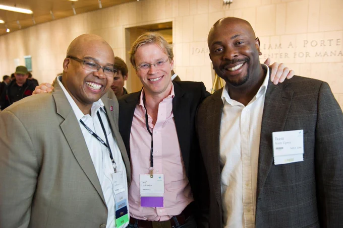Three individuals are standing together at an event, smiling.