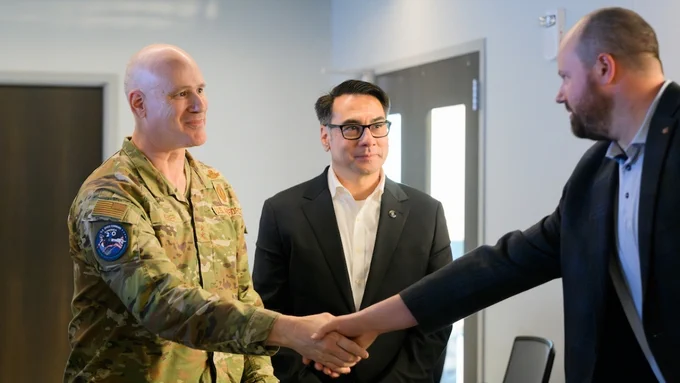 Image of three people, two of them shaking hands.
