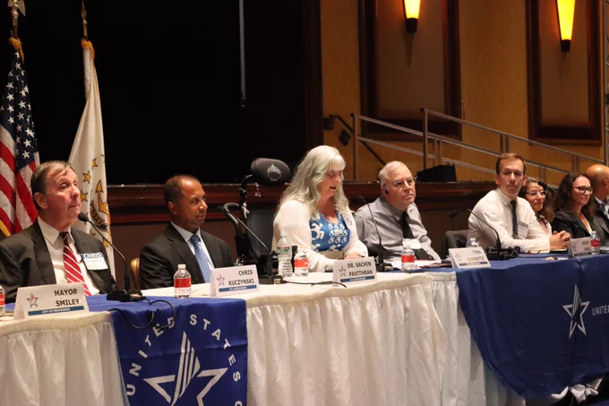 Members of the Access Board sit at the head table as Vice-Chair Tina Guenette speaks.