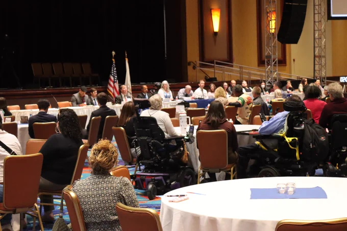 The audience sits in attendance at the town hall.