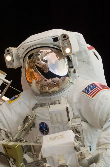 Astronaut John Grunsfeld poses for a picture, with the reflection of Hubble, Earth, and astronaut Andrew Feustel in his helmet.