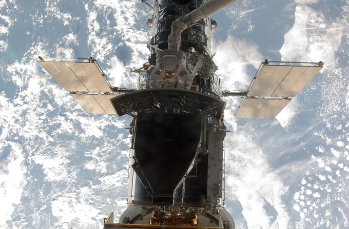 With Earth in the background, Hubble is seen with astronaut Andrew Feustel completing servicing work.