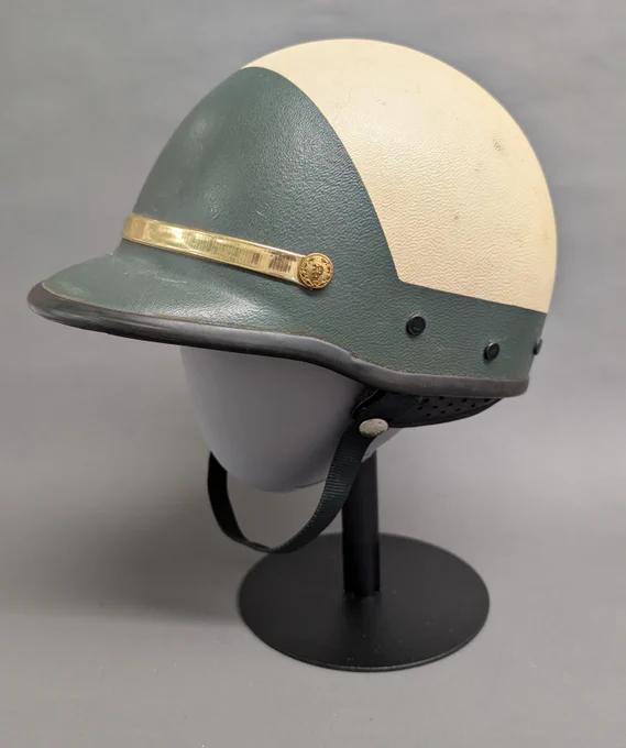 Vintage two-tone motorcycle helmet with green and creampanels and a gold decorative band.