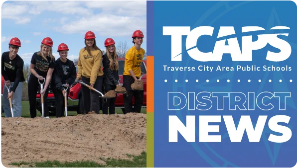 Six people in hard hats stand in a dirt pile. A blue banner behind them reads "TCAPS DISTRICT NEWS".