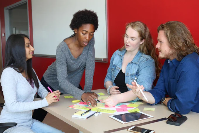 A group of four people is collaborating at a table covered with colorful sticky notes. 