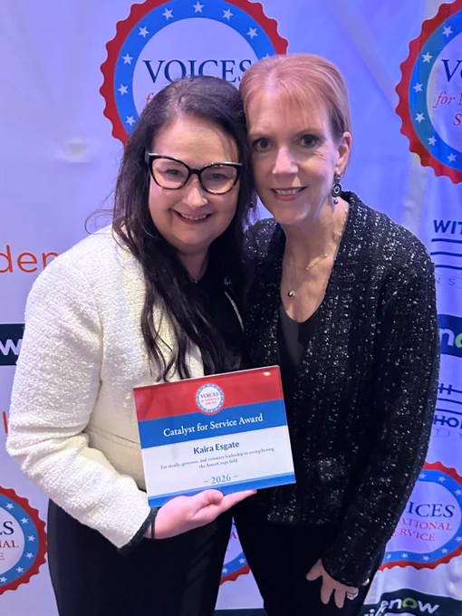 Two people smiling with plaque "Catalyst for Service" award.