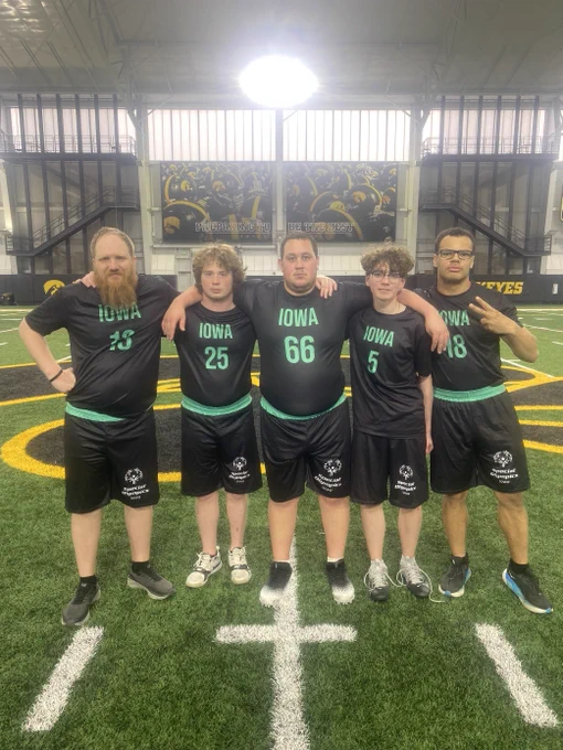 Five flag football players stand together wearing matching uniforms.