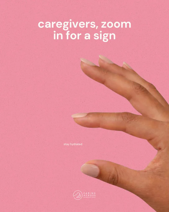 A hand making a pinching gesture is zoomed in against a pink background with the words "caregivers, zoom in for a sign" above. The words "stay hydrated" are near the thumb. The bottom shows the logo of "Caring Across.
