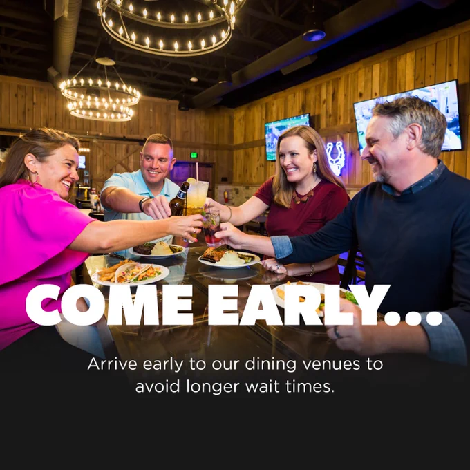 A group of four people are enjoying a meal at Valley Tower Bar & Grill, raising their drinks in a toast. Plates of food and bright lighting create a lively atmosphere. The text reads, "COME EARLY... Arrive early to our dining venues to avoid longer wait times.