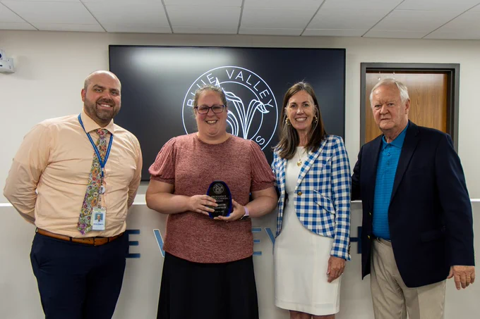 Oak Hill Elementary's Elizabeth Brassfield holding an Excellence in Education Award, standing and smiling with district and school leadership.