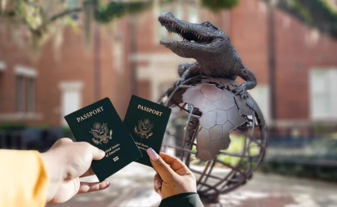 Hands holding United States passports in front of the "Gator Ubiquity" bronze sculpture located outside Heavener Hall at the University of Florida