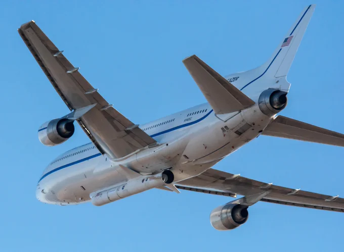 A Stargazer aircraft flying in the air with a Pegasus rocket attached to the bottom. The photograph is taken from the ground and looking at the unside of the aircraft, where the rocekt is attached. (Credit: NASA/Randy Beaudoin)