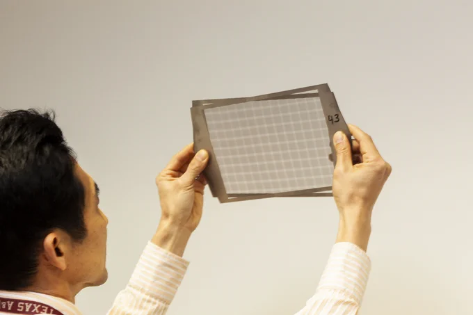 Scientist Seungjoon Lee holds prototype single tungsten sheets up to the light.