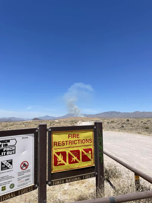 Smoke rising behind fire restrictions poster on the kiosk in Tonto National Forest. 