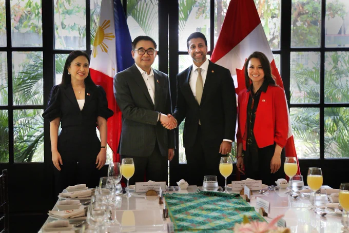  Minister Sidhu shaking hands with the Philippines’ Secretary Go. The Philippines’ Secretary Roque is standing to their left and Minister Valdez is standing to their right. In the background are the Canadian and Philippines’ flags.