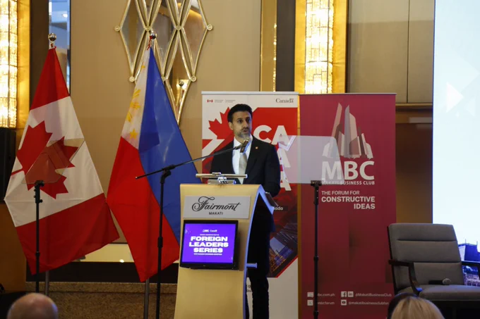  Le ministre Sidhu se tient debout derrière un podium et s'adresse à l'auditoire. À sa gauche se trouvent les drapeaux du Canada et des Philippines.