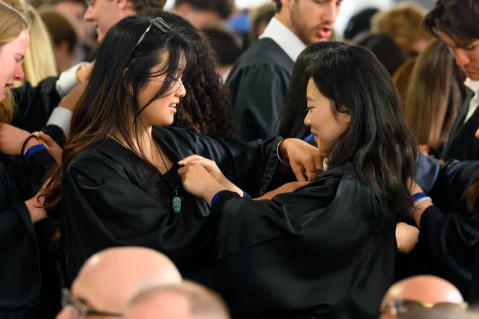 Two students pin alumni pins on each other during Senior Convocation.
