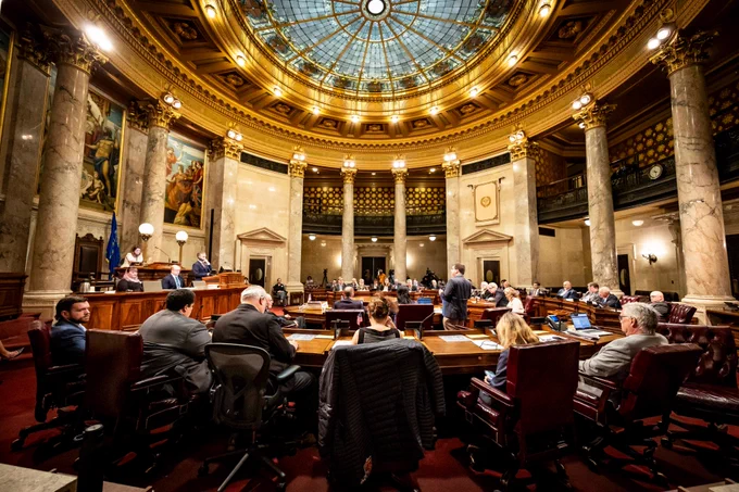 Wide angle photo of the Senate Chambers. State Sen. Mark Spreitzer is standing and speaking.