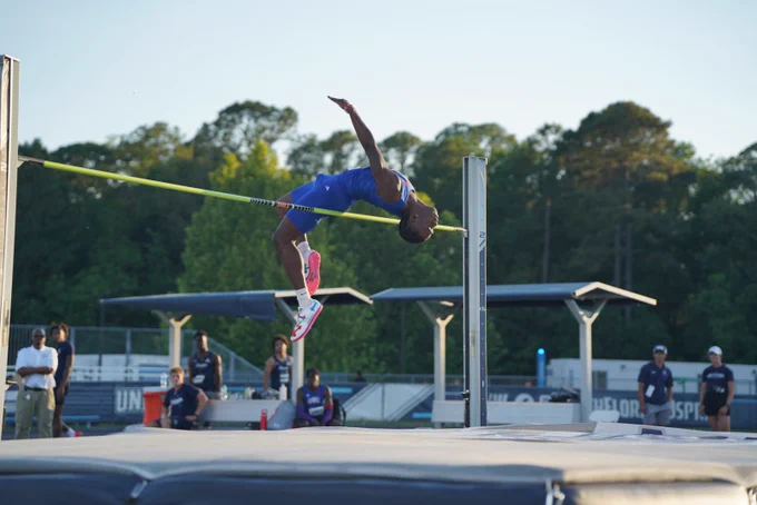 track athlete in blue jumping high jump at a track meet