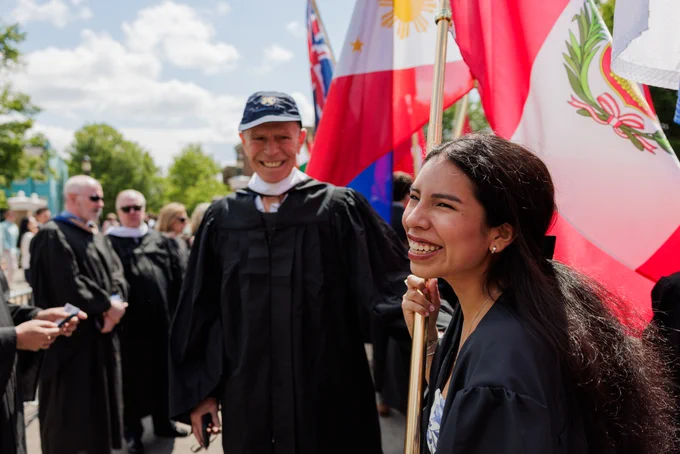 a woman holding a flag smiles out over a crowd