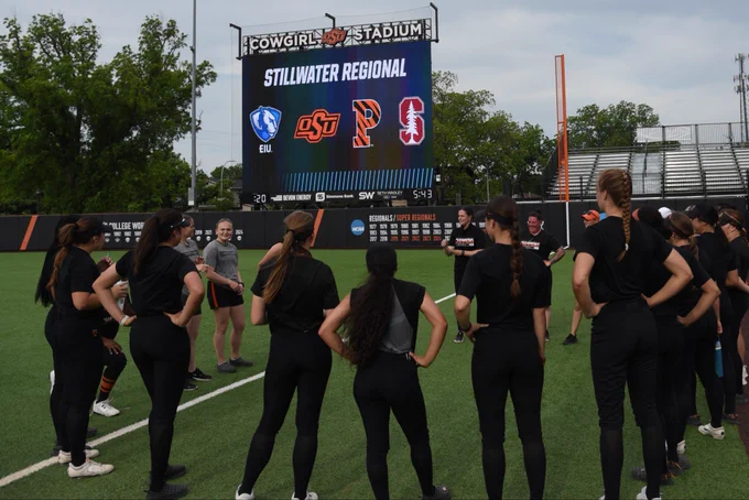 Players stand circled in front of the scoreboard