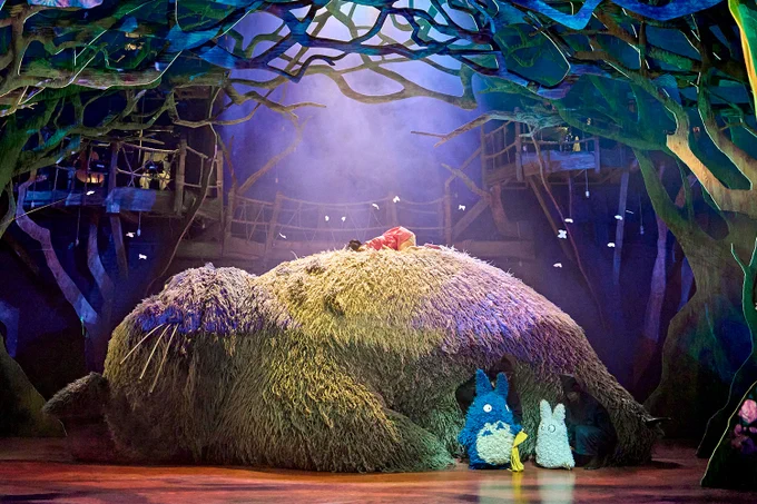 A photo showing a group of puppets on a warmly lit stage 