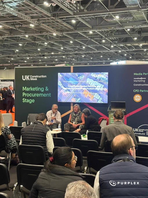 A panel discussion at UK Construction Week focusing on marketing and procurement in the construction industry. The scene captures a professional and collaborative atmosphere.