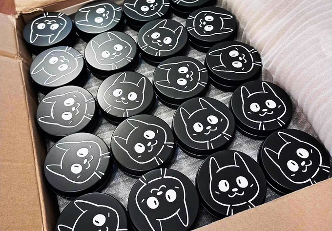 A box of black guitar pick tins featuring a graphic of Bit the cat, one of the Bits & Bops mascots.