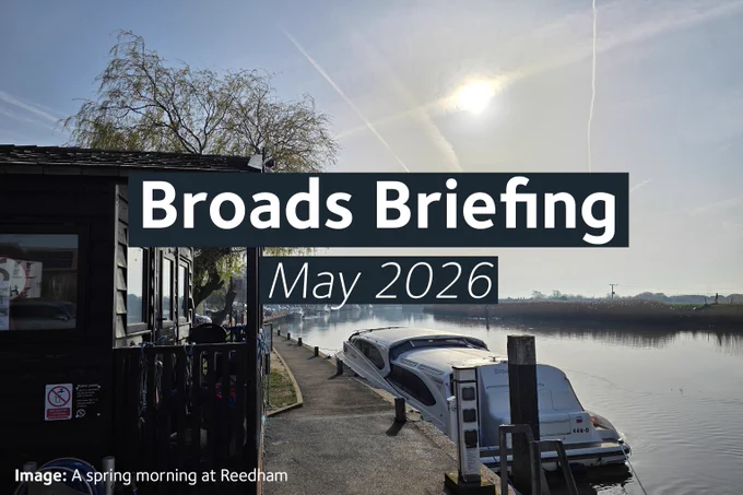 A morning view across the quay at Reedham, showing the moorings, Rangers hut and a moored boat with a moored vessel. The sky shows a hazy sunny morning. Overlaid text reads “Broads Briefing - May 2026”. A small caption at the bottom states: “Image: A spring morning at Reedham”.