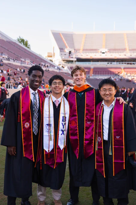 Four grads pose for a photo during graduation.