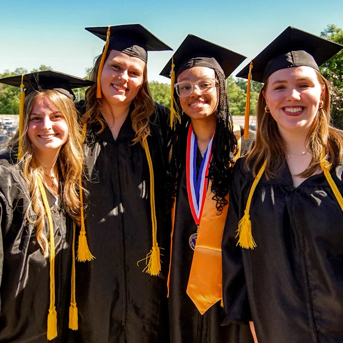 A group of female graduates pose for a picture on graduation day.