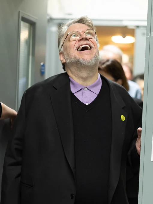A man, walking through an internal door, and looking upwards in amazement.