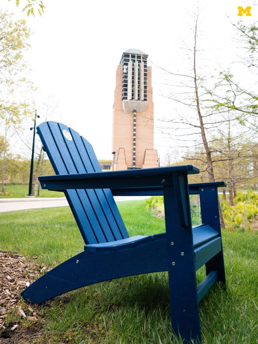 An Adirondack chair on North Campus with Lurie Tower in the background.
