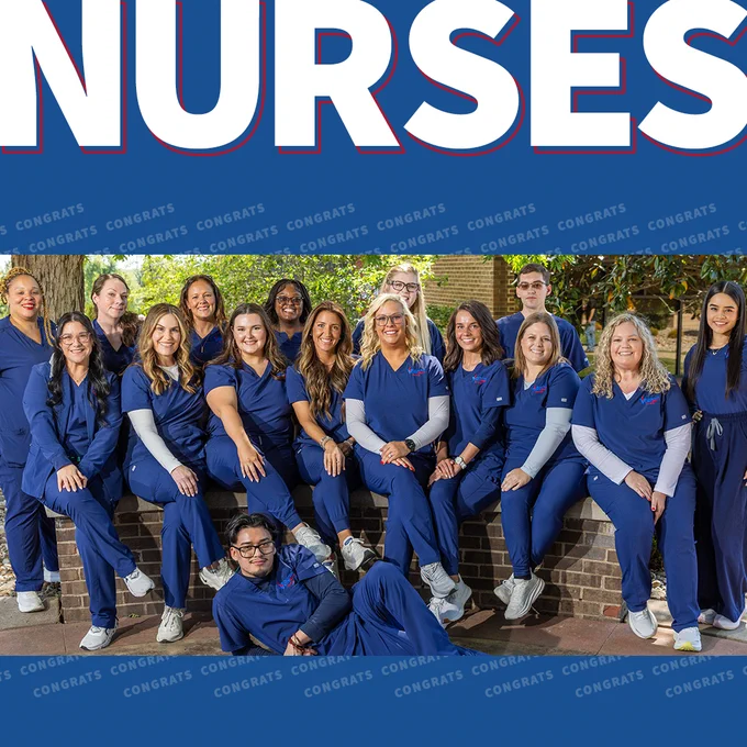 ‘Nursing’
Recent nursing graduates are smiling, all wearing matching blue scrubs. One person is lying on the groud beneath the other grads.