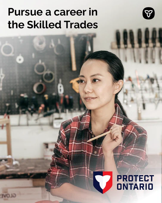 A smiling woman standing in a workshop with tools in the background