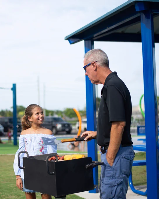 Grandfather talking to granddaughter while grilling