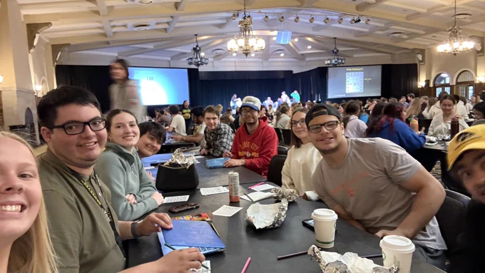 Students sit around a table playing Bingo