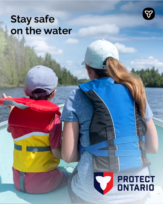 Text: Stay safe on the water
A person and a child sitting in a boat wearing lifejackets on the water. 
