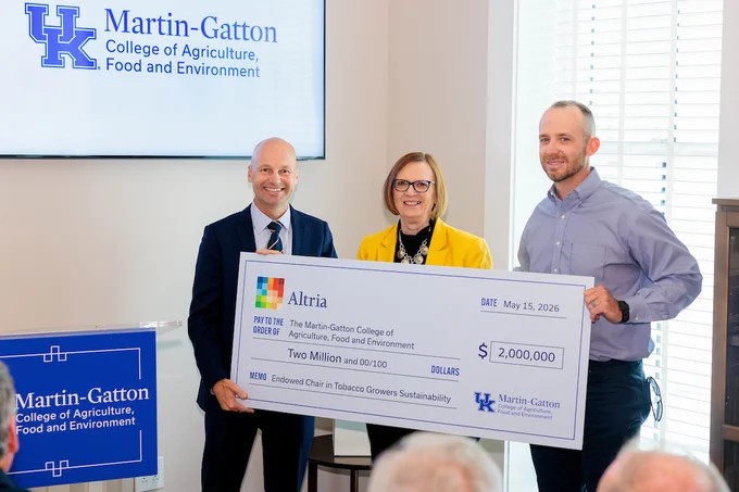 Jon Moore, President and CEO of Philip Morris USA, Martin-Gatton CAFE Dean Laura Stephenson, and Kentucky Commissioner of Agriculture Jonathan Shell hold up a large check from Altria to the University of Kentucky. 