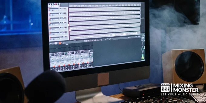 A modern music studio with audio mixer and computer screen displaying tracks.