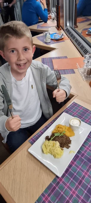 Austin is holding his knife and fork ready to tuck into his haggis, neeps and tatties