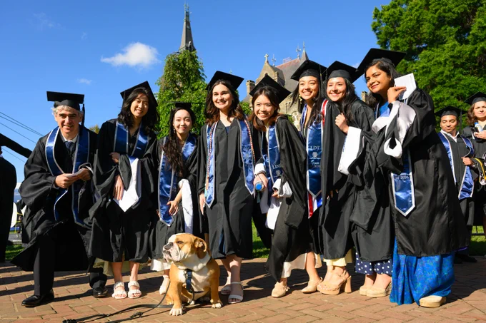 A group of graduates wearing Georgetown DSAN tassels pose with Jack the Bulldog.