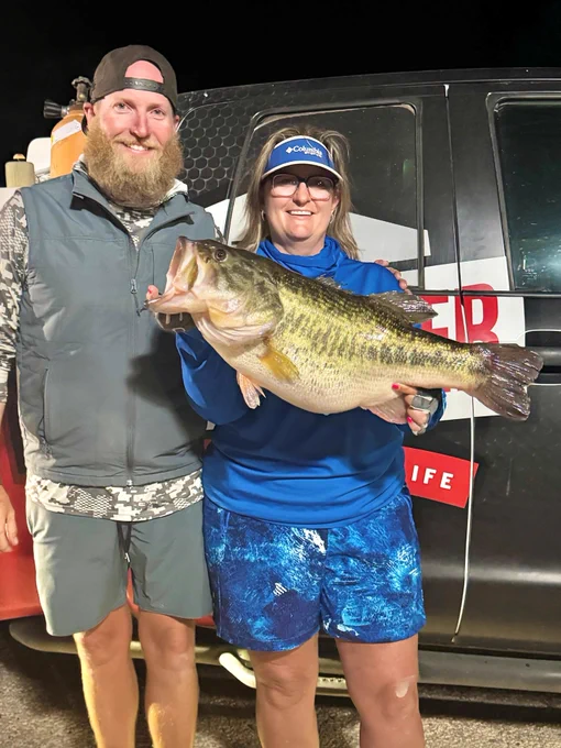 Fishing guide poses with woman holding big largemouth bass
