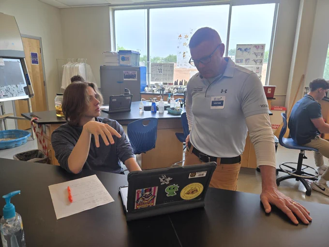 Dr. Kevin Christiansen speaks with studient at a desk in a veterinary classroom about veterinary cardiology topics.