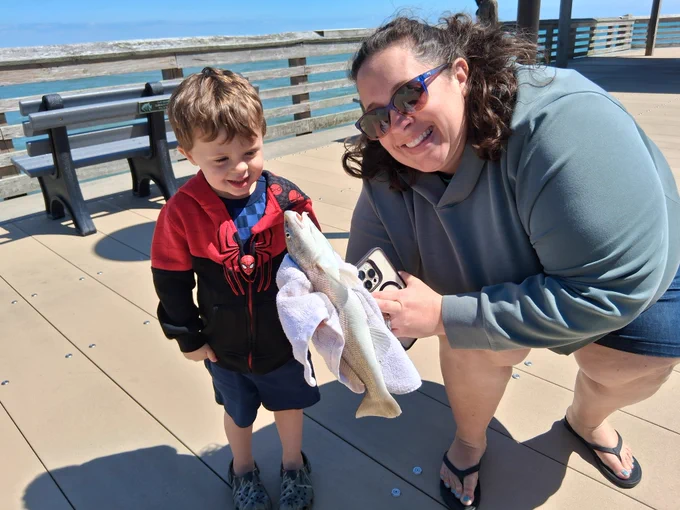 Mom shows her son a nice sea mullet she just landed on ocean fishing pier