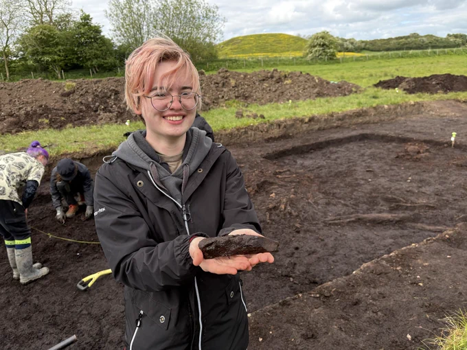 A student holds a waterlogged wooden stake.
