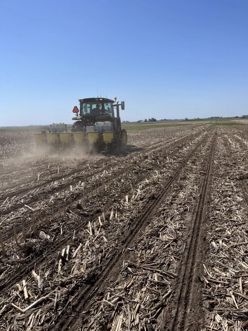 Tractor pulling 6-row planter in corn stubble.